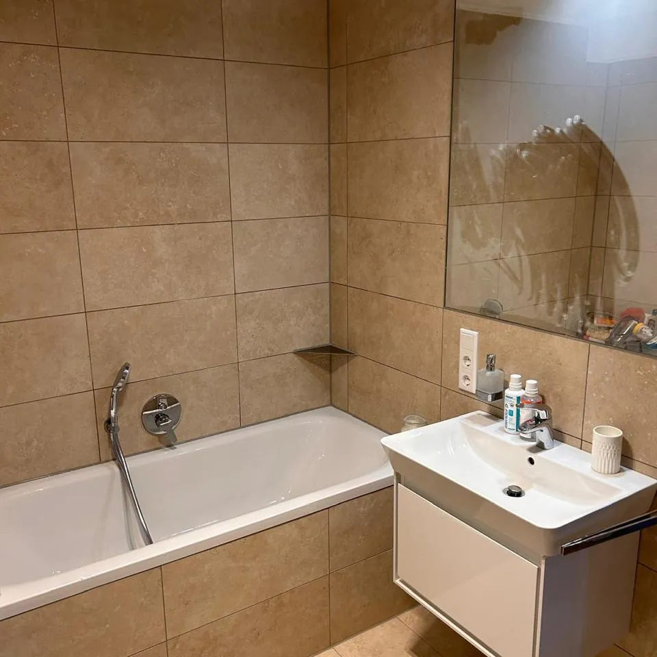 Dasselbe Bad nach der Sanierung: neu gefliest, mit Badewanne und Waschtisch