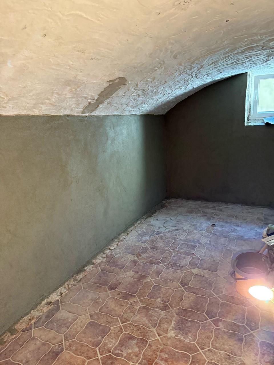Gewölbekeller mit rohen Wänden und altem Fliesenboden vor dem Ausbau