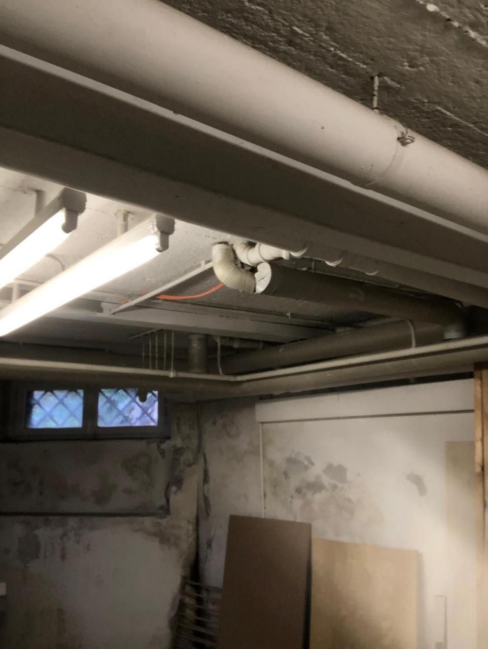 Kellerraum mit offenen Leitungen und fleckigen Wänden vor dem Ausbau